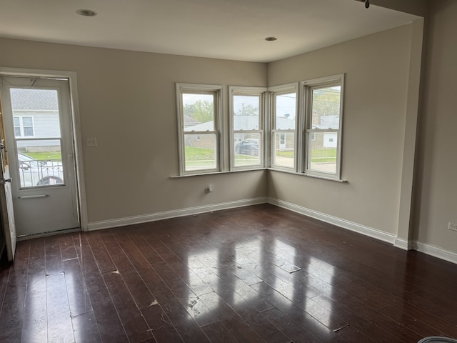 unfurnished dining area featuring a wealth of natural light, dark wood-style floors, and baseboards
