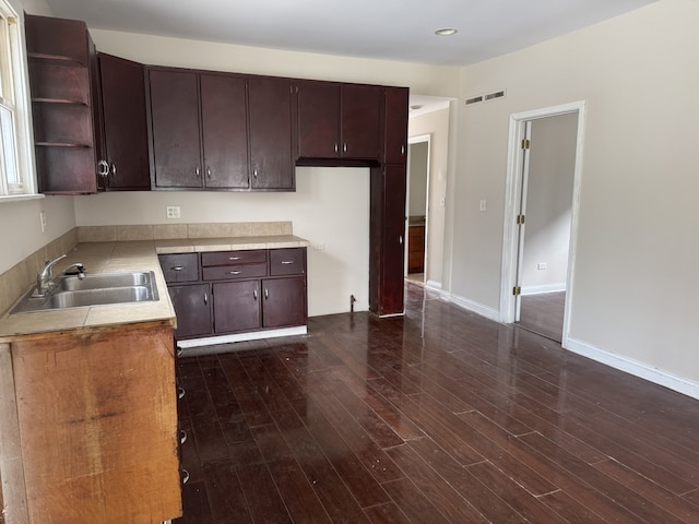 kitchen featuring dark wood finished floors, open shelves, dark brown cabinets, a sink, and visible vents