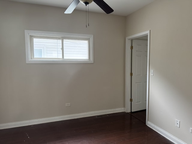 empty room with baseboards, visible vents, ceiling fan, and dark wood-style flooring