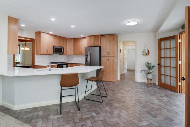 kitchen featuring baseboards, a peninsula, appliances with stainless steel finishes, and tasteful backsplash