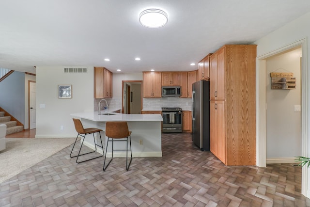 kitchen with appliances with stainless steel finishes, a peninsula, open floor plan, a kitchen bar, and visible vents