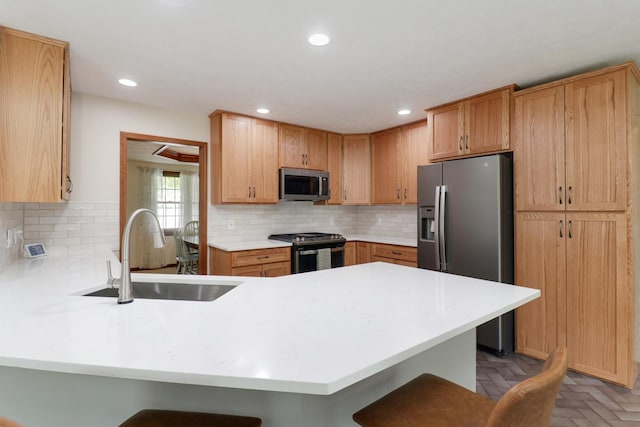 kitchen with stainless steel appliances, a kitchen bar, a sink, and a peninsula