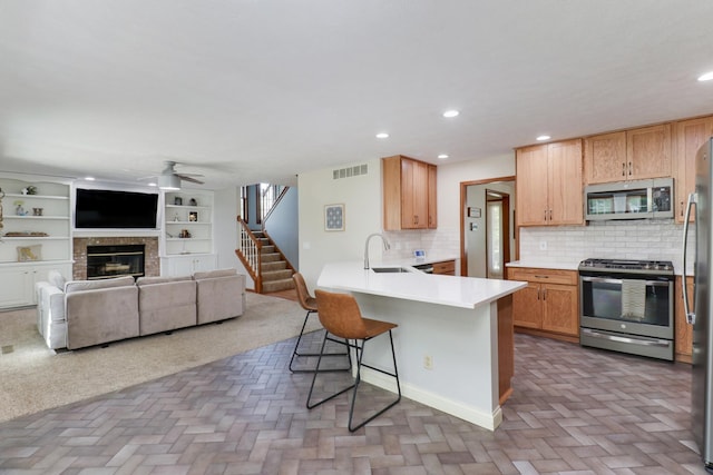 kitchen with ceiling fan, visible vents, appliances with stainless steel finishes, a sink, and a breakfast bar