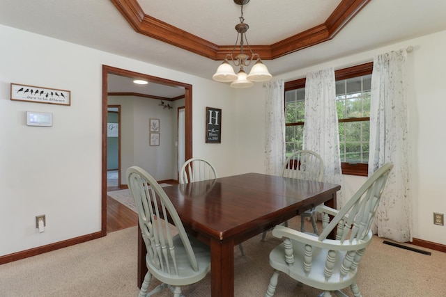 dining room with visible vents, crown molding, baseboards, a raised ceiling, and carpet floors