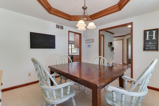 carpeted dining space with visible vents, a raised ceiling, baseboards, an inviting chandelier, and ornamental molding