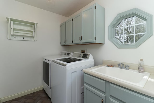 laundry area with cabinet space, separate washer and dryer, baseboards, and a sink