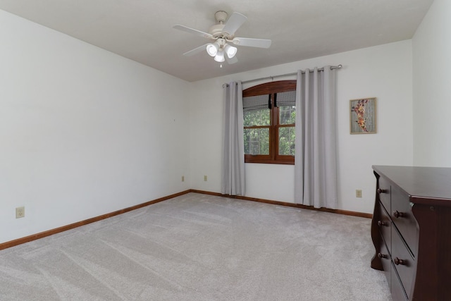 spare room featuring baseboards, ceiling fan, and light colored carpet