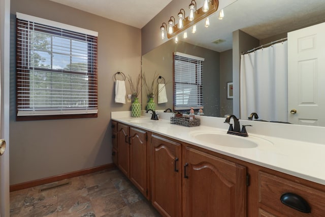 full bath featuring baseboards, a sink, visible vents, and stone finish floor