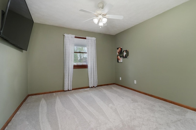 unfurnished room with baseboards, ceiling fan, and light colored carpet
