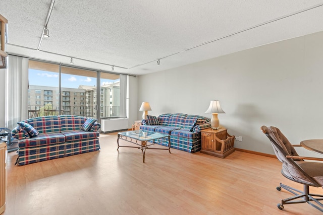 living room with track lighting, a textured ceiling, baseboards, and wood finished floors