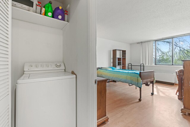 laundry room featuring a textured ceiling, washer / dryer, and wood finished floors