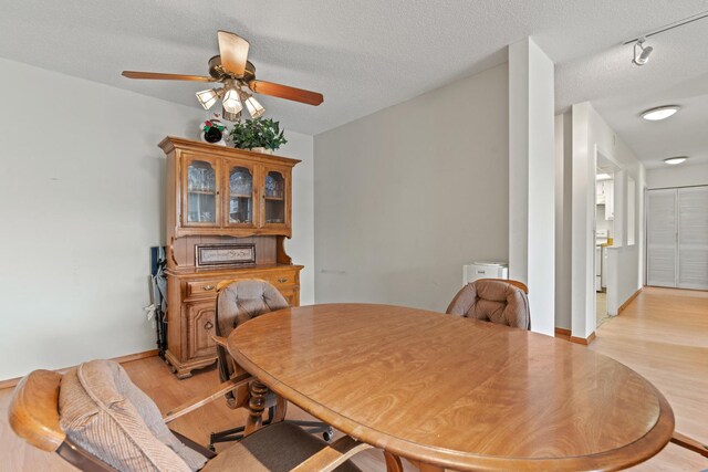dining room featuring a textured ceiling, ceiling fan, baseboards, and light wood-type flooring
