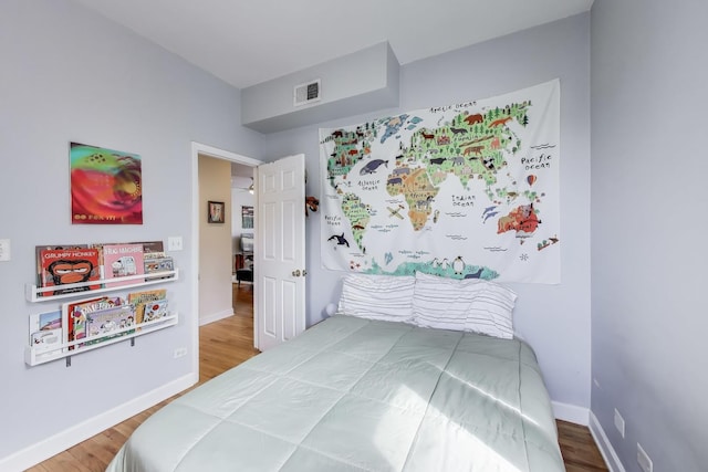 bedroom featuring baseboards, wood finished floors, and visible vents