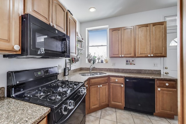 kitchen featuring light tile patterned floors, brown cabinetry, a sink, and black appliances