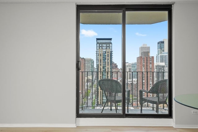 doorway with a view of city, floor to ceiling windows, baseboards, and wood finished floors