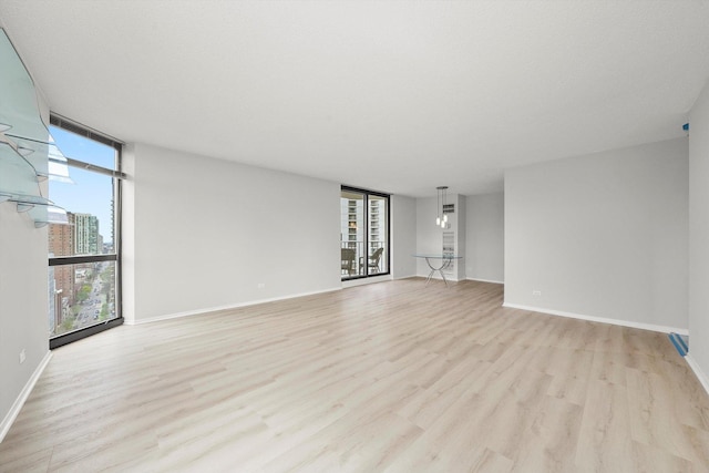 unfurnished living room featuring baseboards, expansive windows, and light wood finished floors