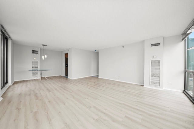 unfurnished living room with baseboards, visible vents, and light wood-style floors