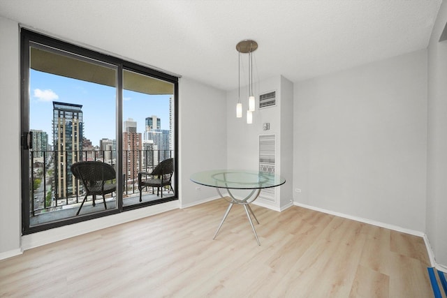 dining room featuring a view of city, baseboards, floor to ceiling windows, wood finished floors, and visible vents