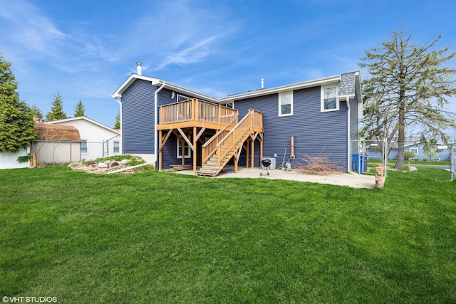 back of property with a wooden deck, fence, stairs, a lawn, and an outbuilding