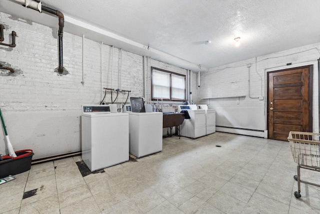 5927 W Addison St Unit 2D, Chicago, IL 60634 - communal laundry room with washing machine and dryer, a baseboard heating unit, a textured ceiling, and brick wall
