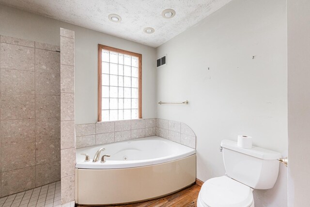 609 Moss Pl, Dixon, IL 61021 - bathroom featuring toilet, wood finished floors, a tub with jets, a textured ceiling, and a tile shower