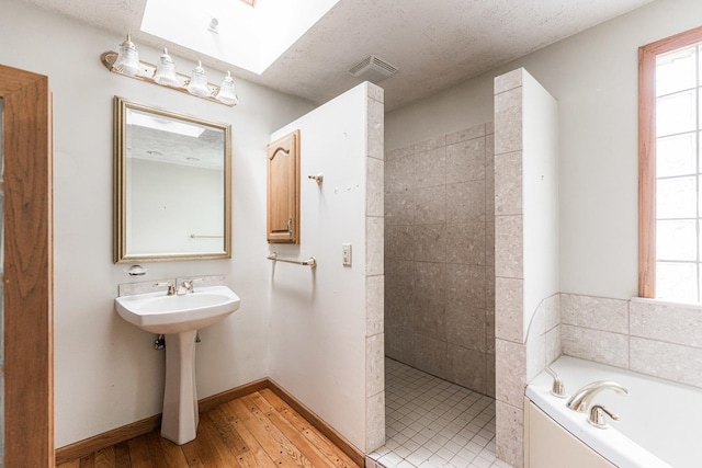 609 Moss Pl, Dixon, IL 61021 - full bath featuring a tile shower, a bath, hardwood / wood-style flooring, a skylight, and baseboards