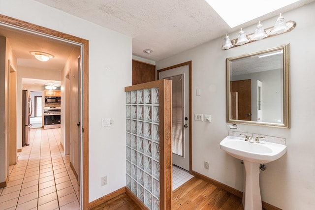 609 Moss Pl, Dixon, IL 61021 - bathroom featuring baseboards, a sink, wood finished floors, a textured ceiling, and ceiling fan