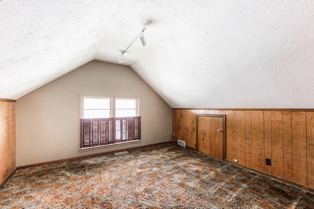 609 Moss Pl, Dixon, IL 61021 - additional living space featuring vaulted ceiling, carpet flooring, a textured ceiling, wood walls, and baseboards