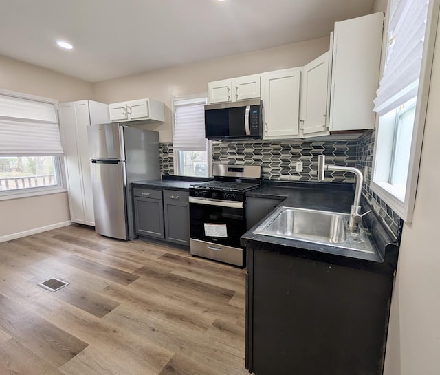 257 Orchard Ave, Kankakee, IL 60901 - kitchen featuring stainless steel appliances, a sink, dark countertops, decorative backsplash, and light wood-type flooring