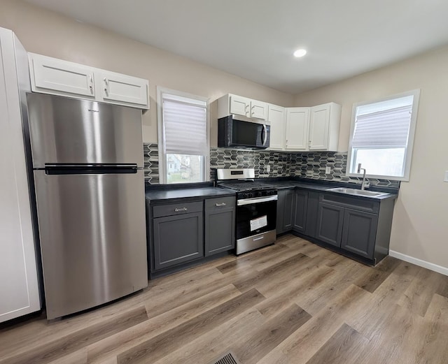 257 Orchard Ave, Kankakee, IL 60901 - kitchen with stainless steel appliances, a sink, dark countertops, white cabinetry, and tasteful backsplash