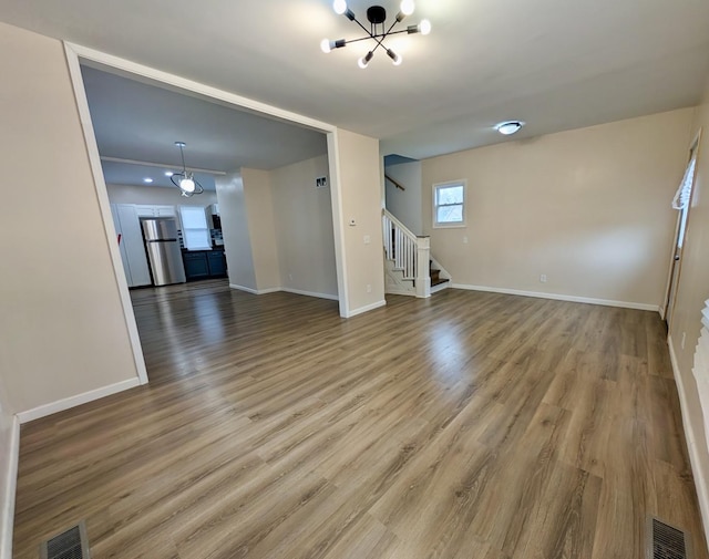 257 Orchard Ave, Kankakee, IL 60901 - unfurnished living room with stairway, a chandelier, baseboards, and wood finished floors