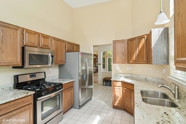 838 Old Checker Rd Unit D-4, Buffalo Grove, IL 60089 - kitchen featuring appliances with stainless steel finishes, a sink, a towering ceiling, light tile patterned floors, and light stone countertops