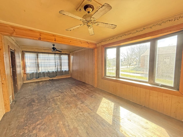 empty room featuring wood finished floors, ceiling fan, and wooden walls