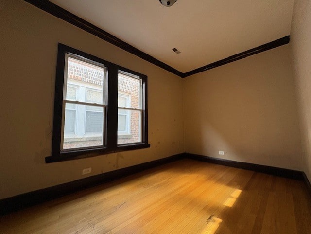 spare room featuring crown molding, visible vents, baseboards, and light wood-style floors