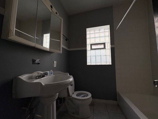 full bath featuring baseboards, toilet, tile patterned flooring, and bathtub / shower combination
