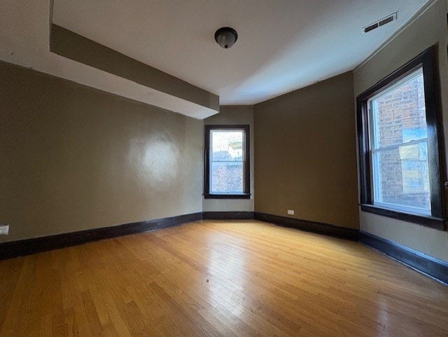 spare room with visible vents, light wood-style flooring, and baseboards