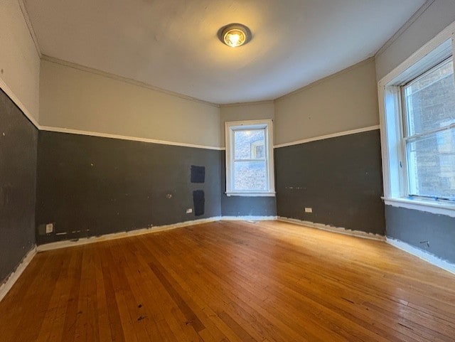unfurnished room with baseboards, ornamental molding, and wood-type flooring