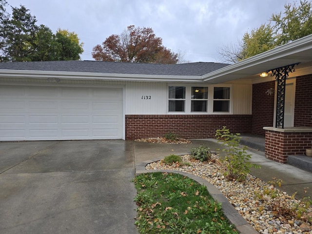 ranch-style home with roof with shingles, concrete driveway, an attached garage, and brick siding