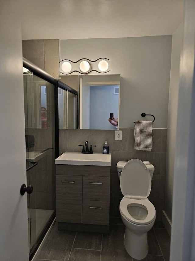 full bath with tile walls, vanity, toilet, a stall shower, and tile patterned flooring