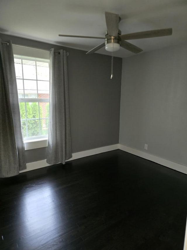 unfurnished room with dark wood-style flooring, ceiling fan, and baseboards
