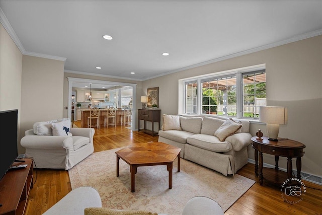 living area with recessed lighting, ornamental molding, and light wood-style flooring