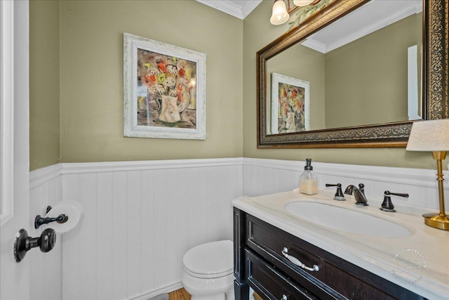 half bath featuring crown molding, vanity, wainscoting, and toilet