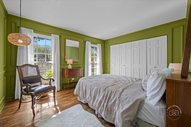 bedroom featuring wood finished floors, a decorative wall, and a closet