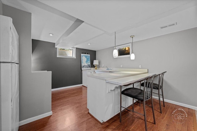 kitchen with visible vents, freestanding refrigerator, baseboards, and wood finished floors