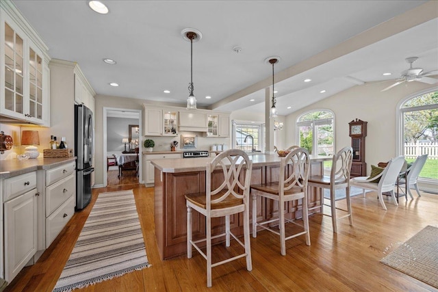 kitchen featuring freestanding refrigerator, lofted ceiling, light wood-type flooring, recessed lighting, and light countertops