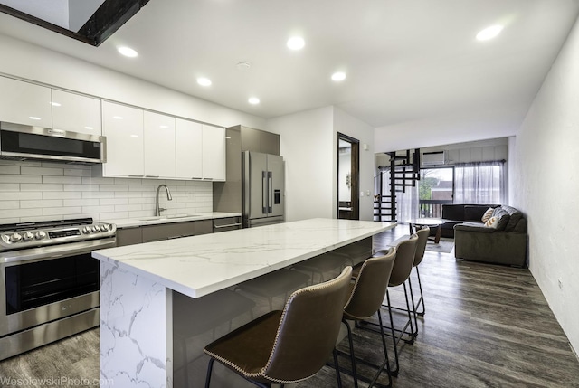 kitchen featuring a breakfast bar area, appliances with stainless steel finishes, backsplash, a sink, and modern cabinets