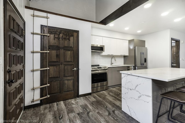kitchen with dark wood finished floors, decorative backsplash, appliances with stainless steel finishes, a sink, and modern cabinets