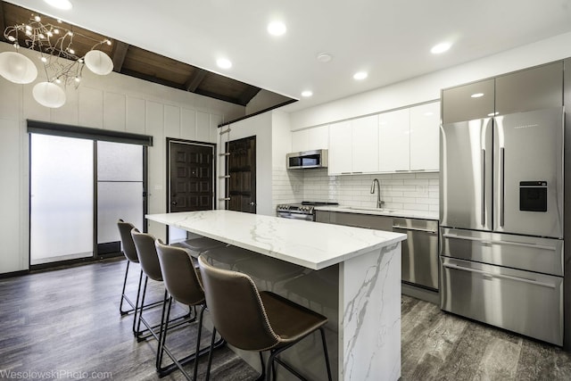 kitchen featuring modern cabinets, a sink, a center island, appliances with stainless steel finishes, and dark wood finished floors