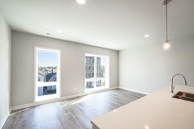 unfurnished living room with baseboards, recessed lighting, wood finished floors, and a sink