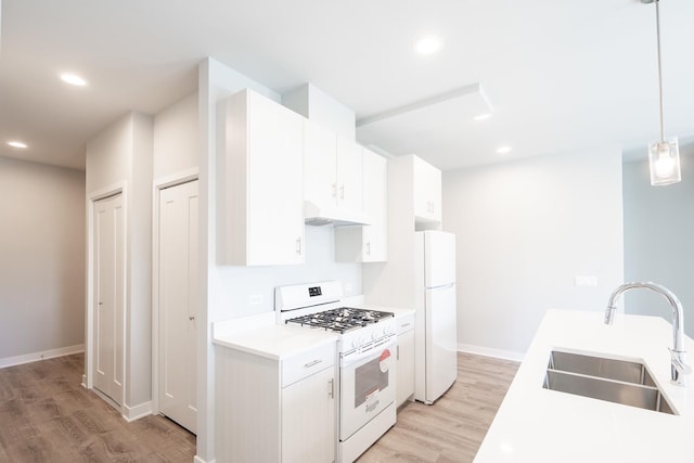 kitchen with white appliances, light wood-style floors, under cabinet range hood, light countertops, and a sink